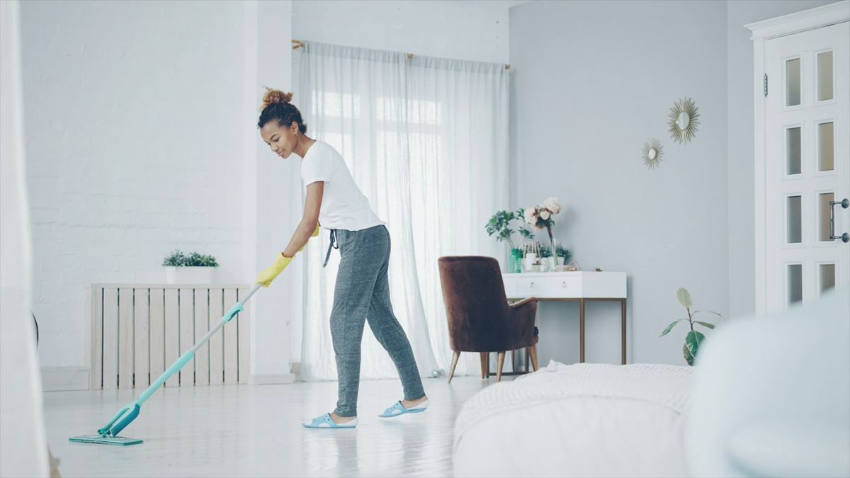 Cleaner mopping the floor of a bright, airy living room