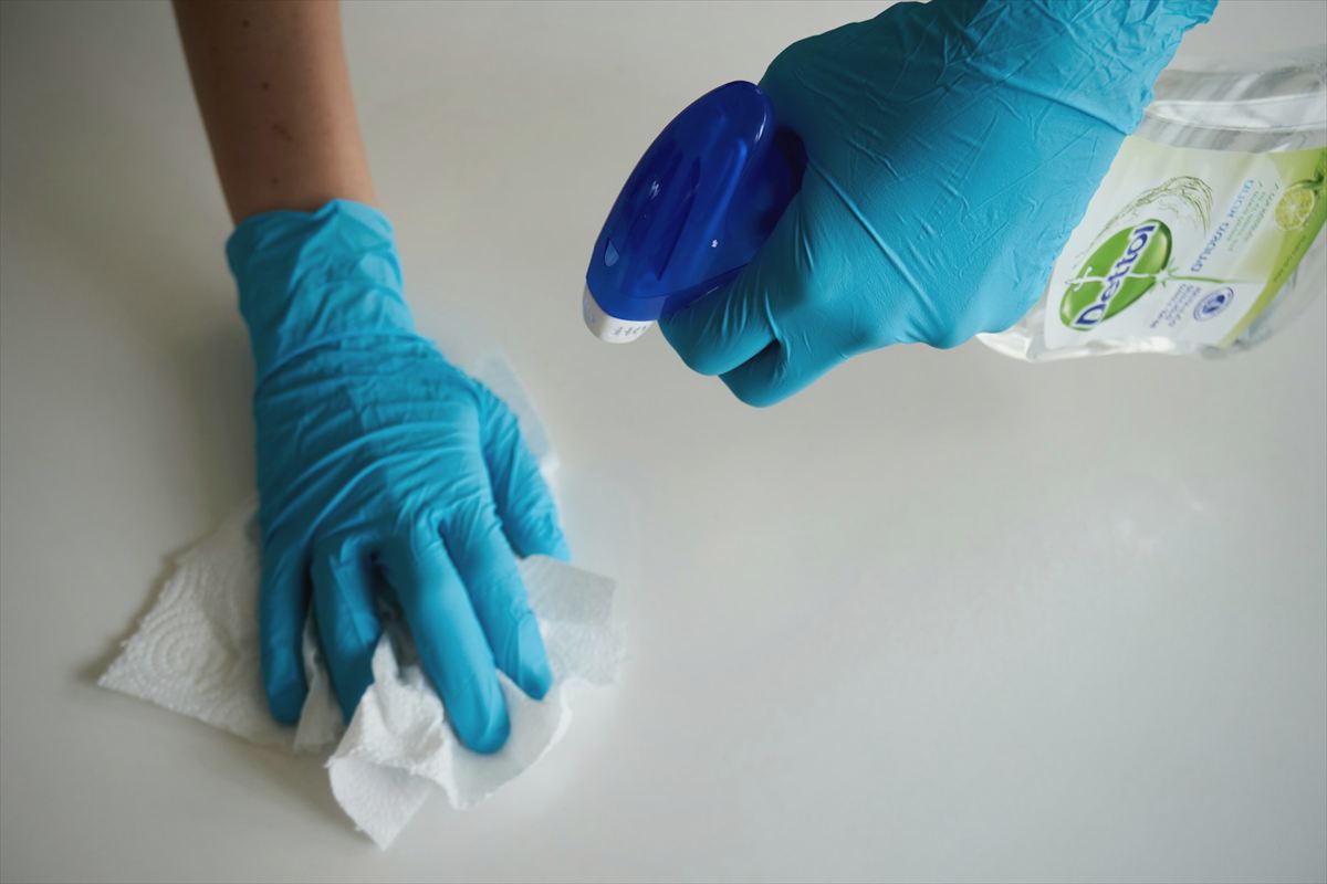 Gloved hands wiping down a clean surface with a spray bottle