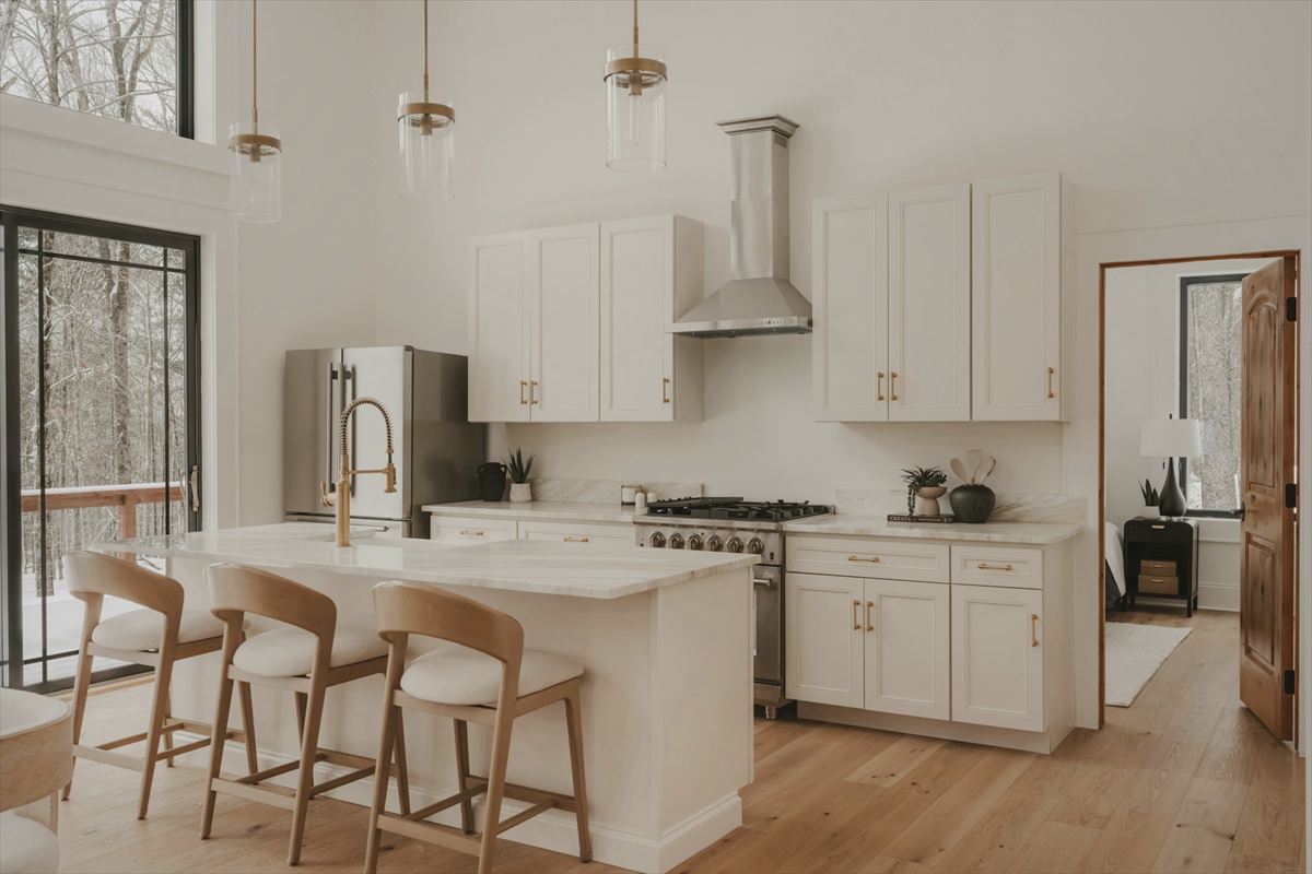 Bright white kitchen with an island and wooden stools